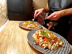 European gay chef strips and cooks noodles with chicken and vegetables.